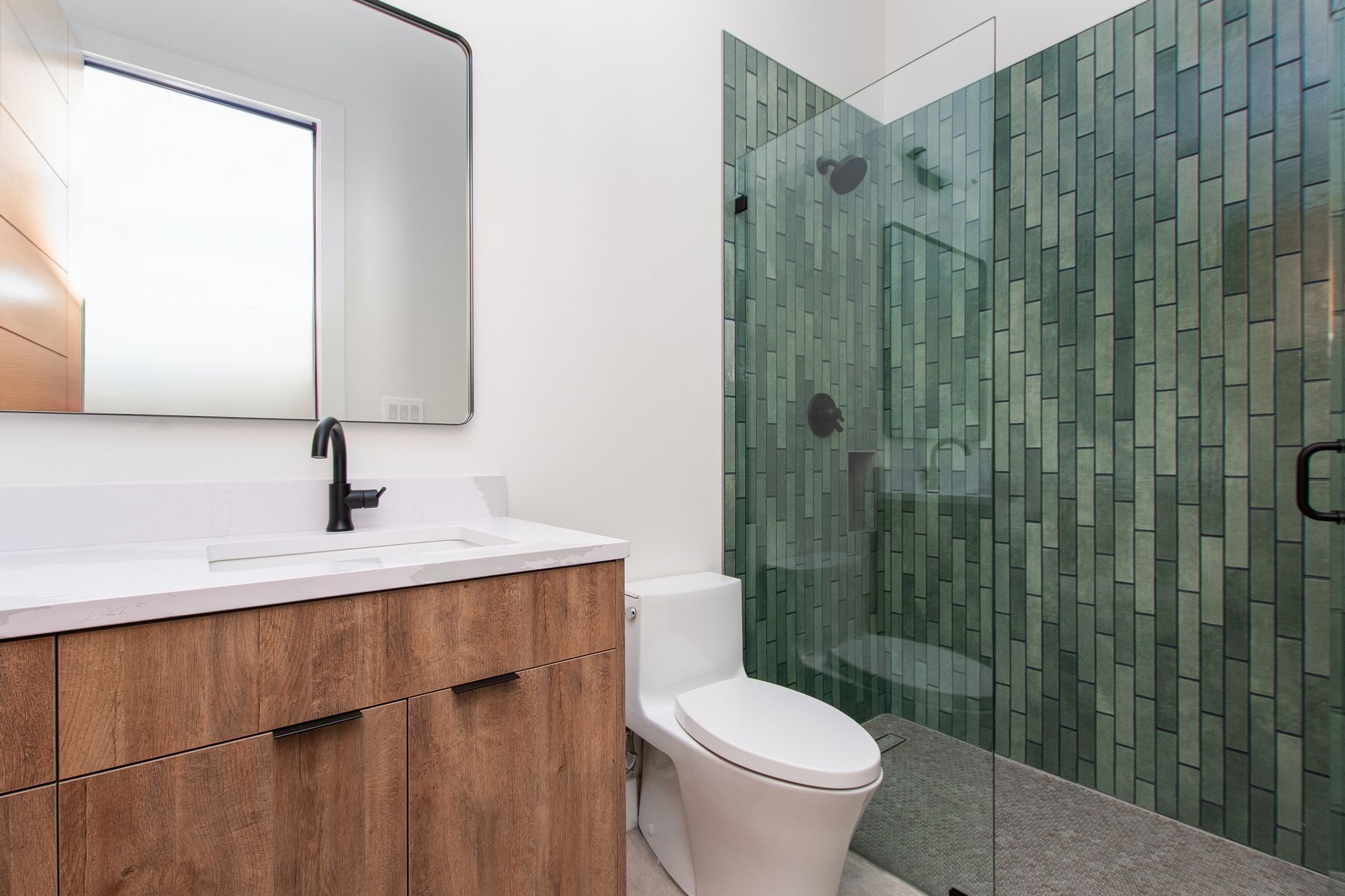 A bathroom with a toilet , sink , mirror and shower.
