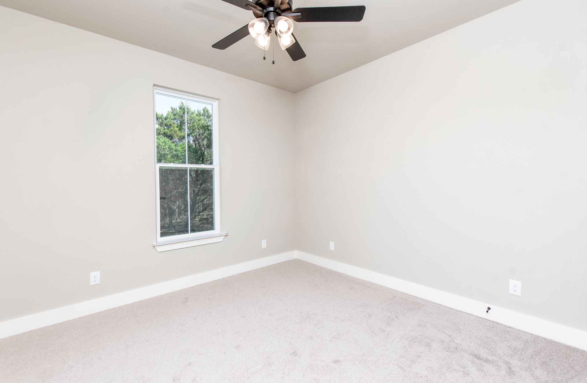 An empty bedroom with a ceiling fan and a window.