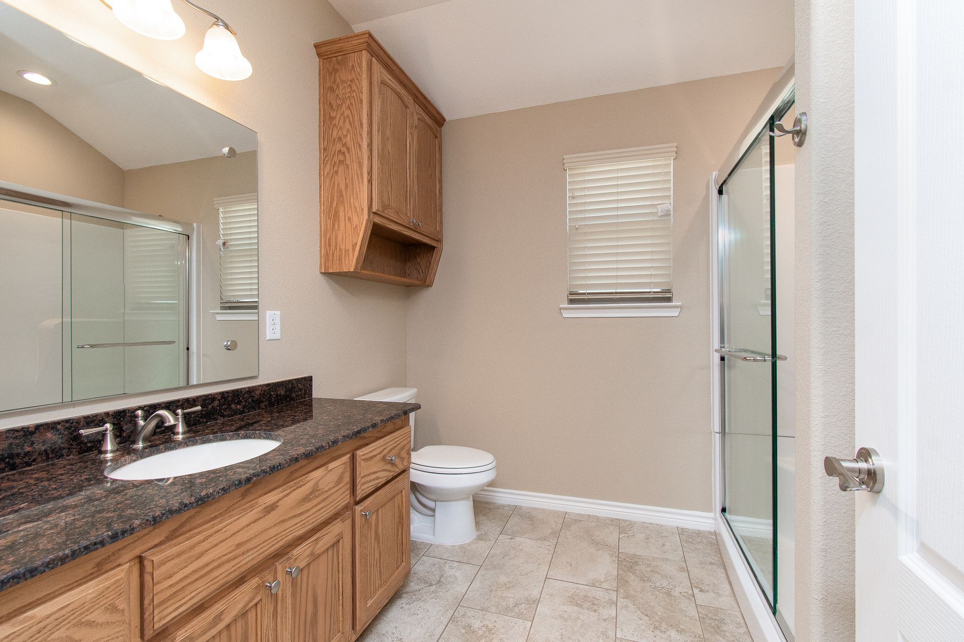 A bathroom with a toilet , sink , mirror and shower.