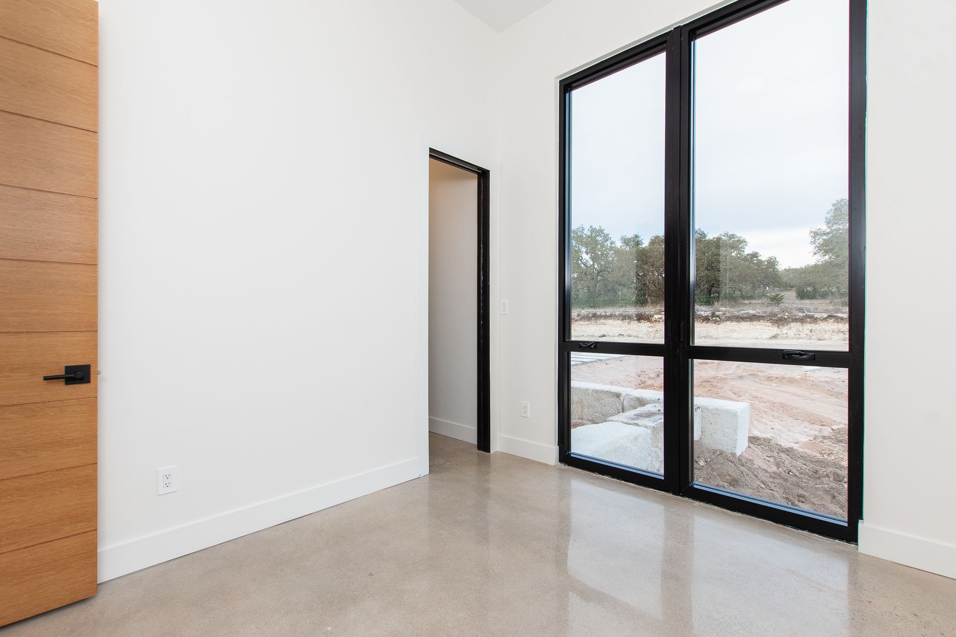 An empty room with two large windows and a wooden door.