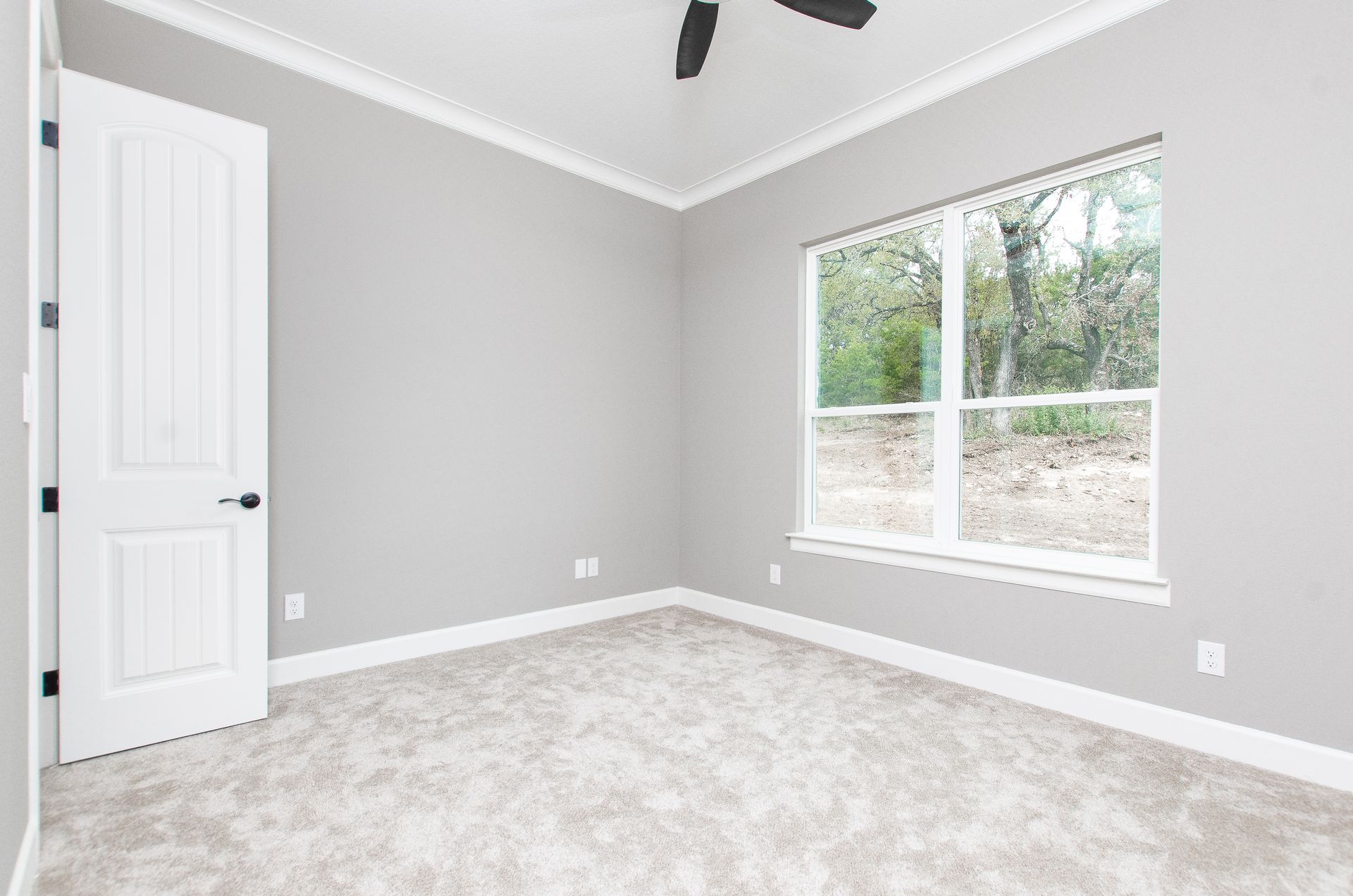 An empty bedroom with a ceiling fan and a window.