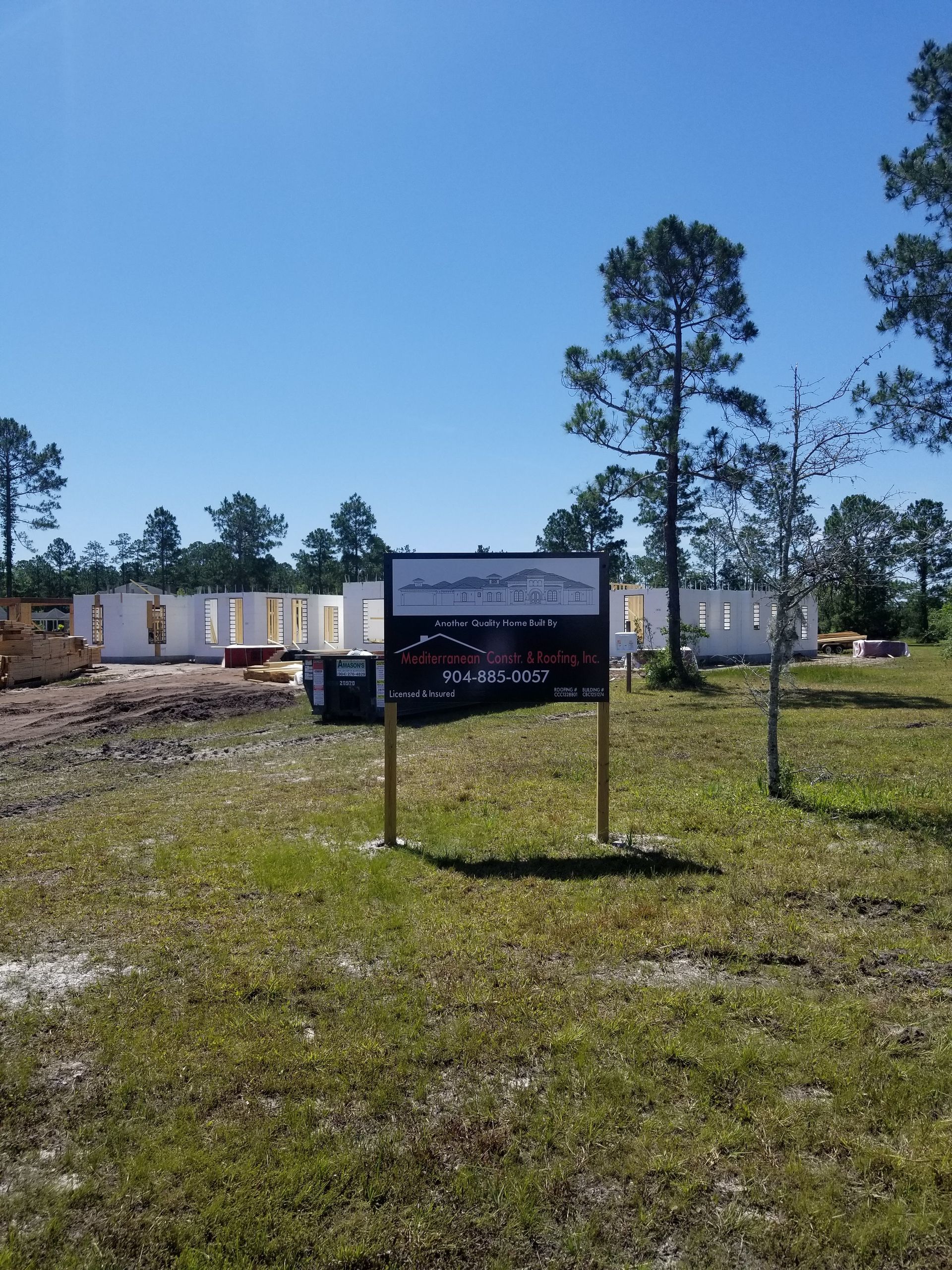 A sign in a grassy field with a building in the background