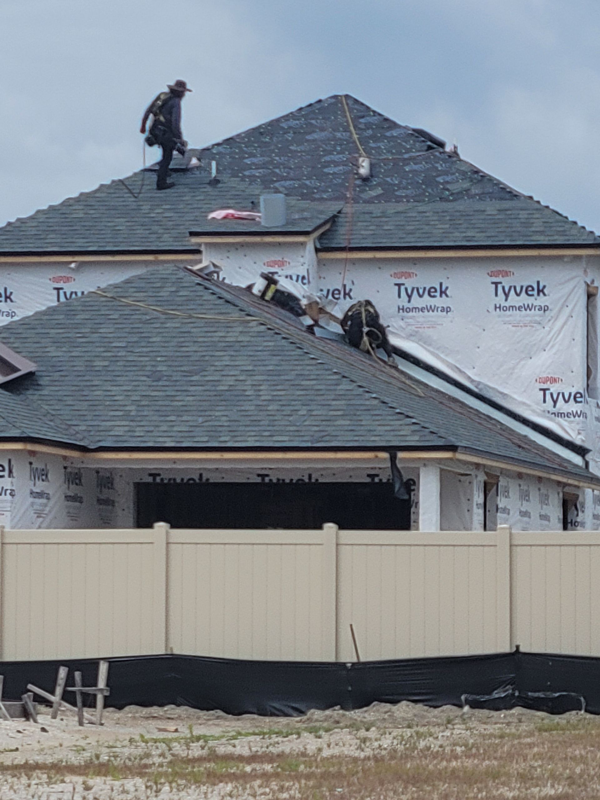 A man is standing on the roof of a house under construction.