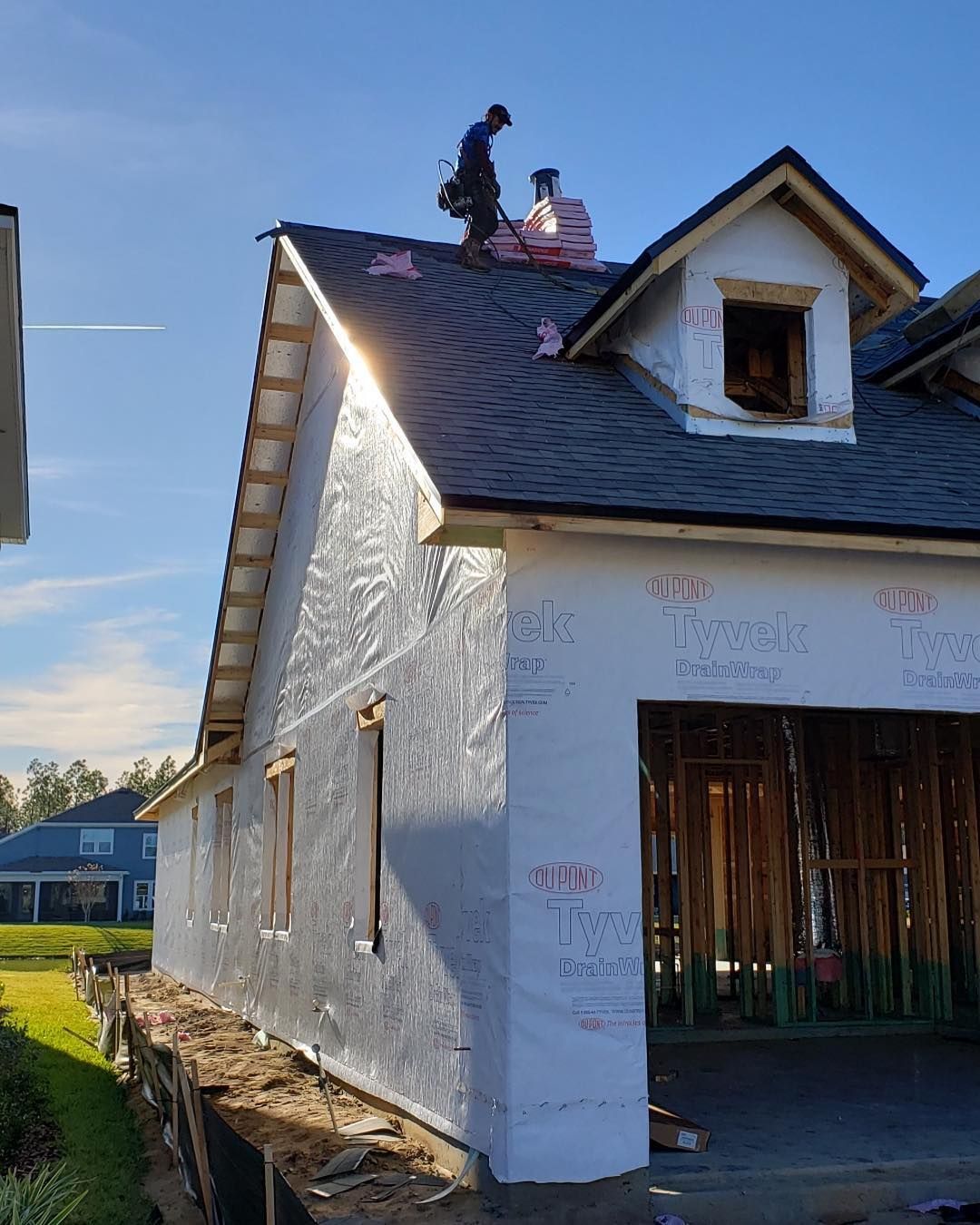 A man is working on the roof of a house under construction.