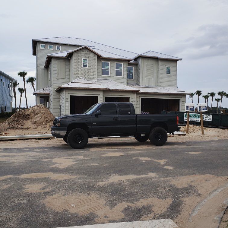 A black truck is parked in front of a house under construction