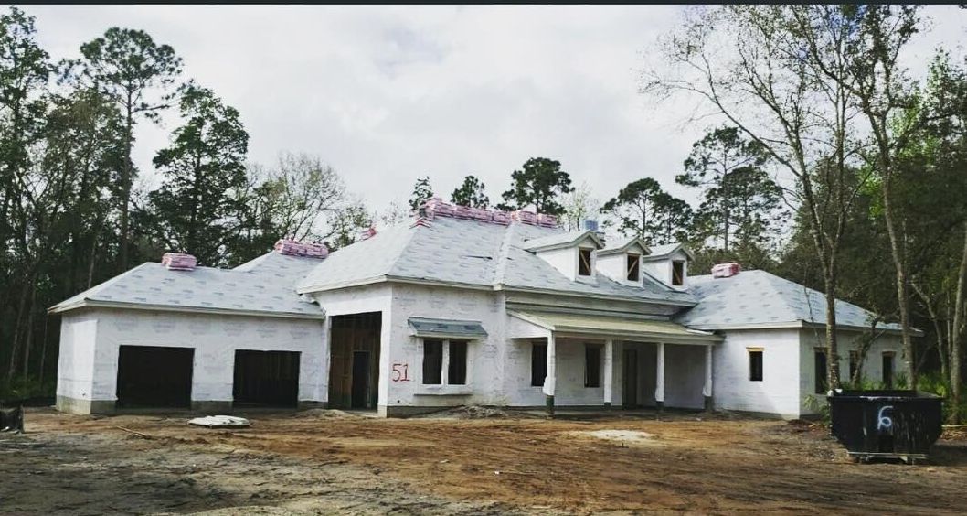 A large white house is being built in the middle of a forest.