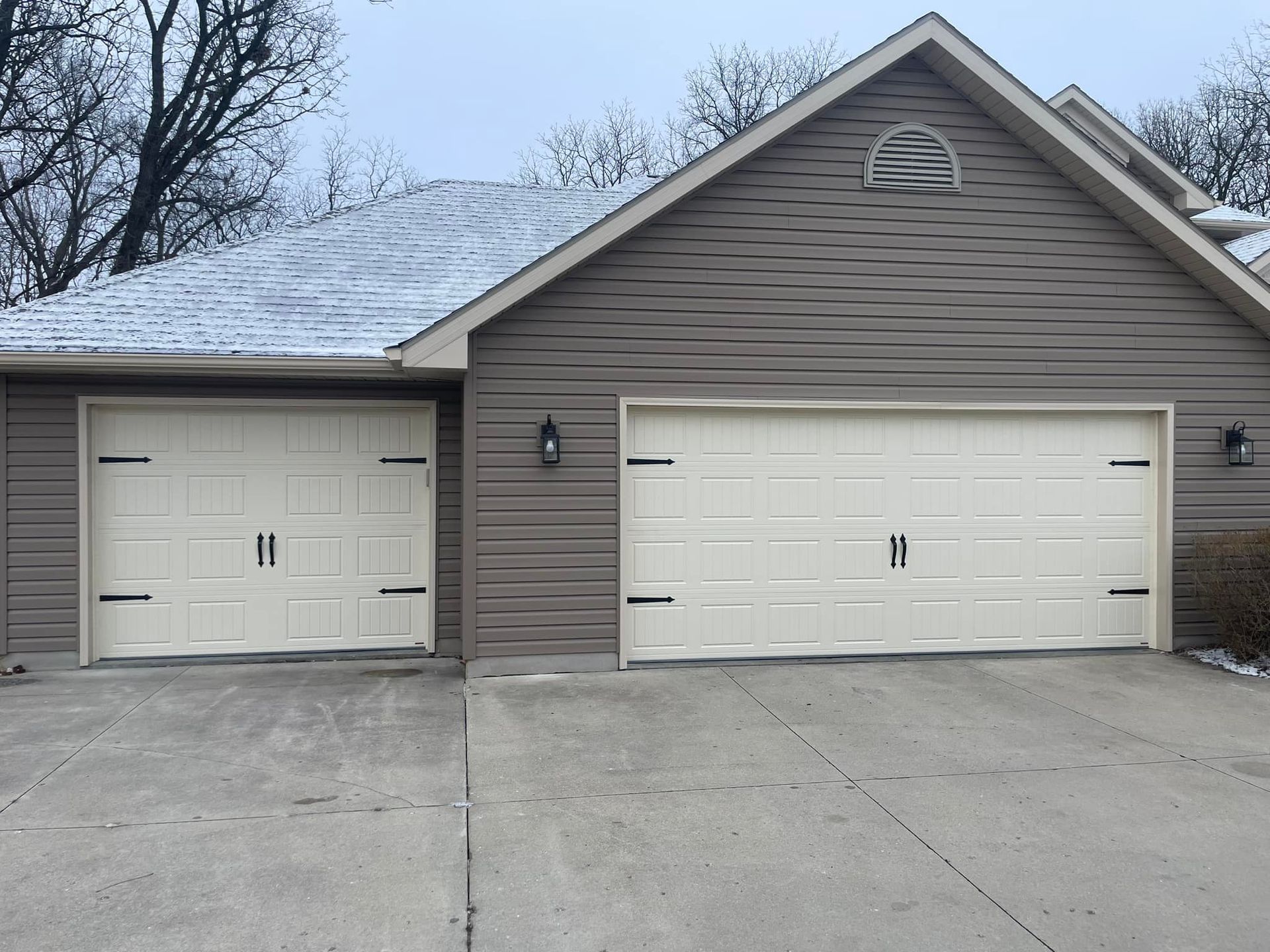 Steel garage door in off-white color brandishing decorative carriage house elements in black.