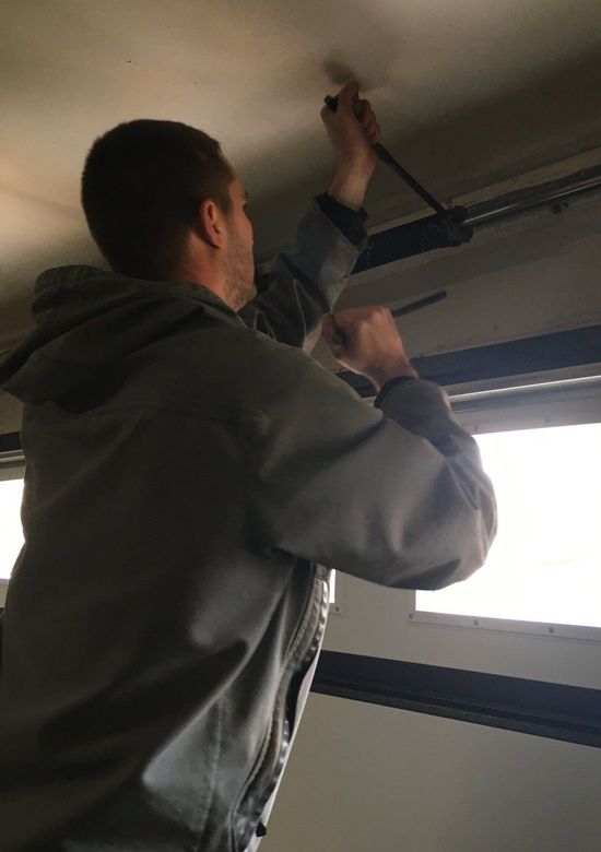 Overhead garage door installer making repairs to the tube shaft