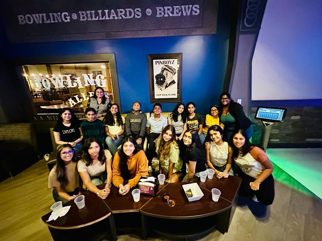 A group of people are posing for a picture in a bowling alley.