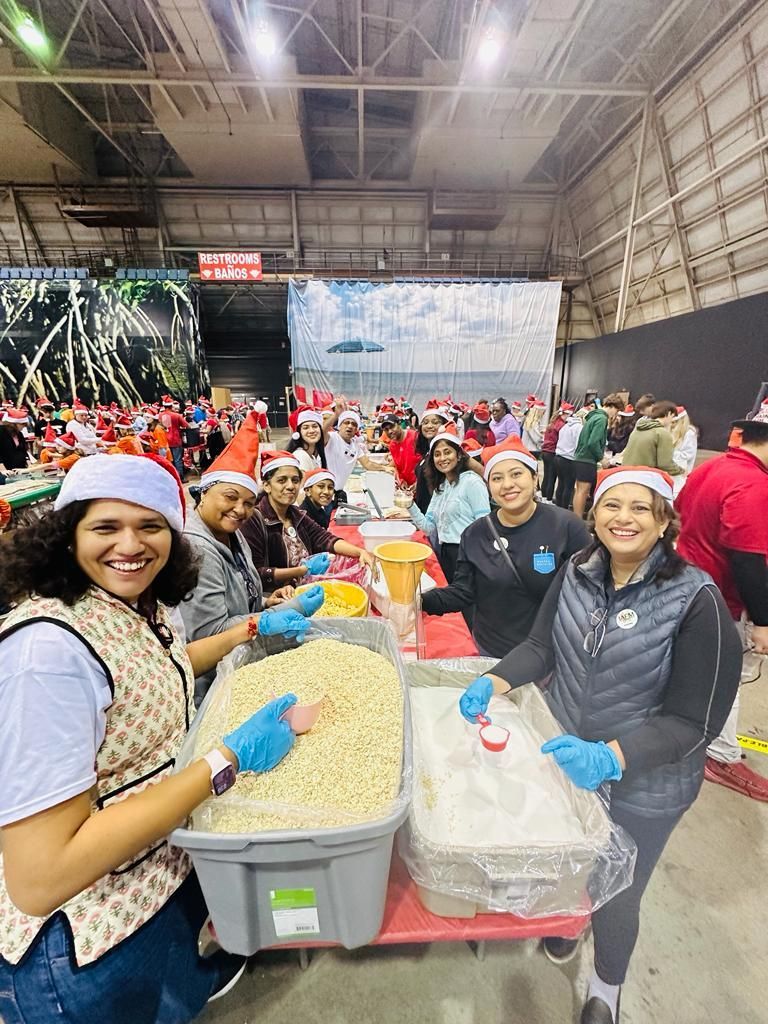 A group of people are standing around a table filled with food.