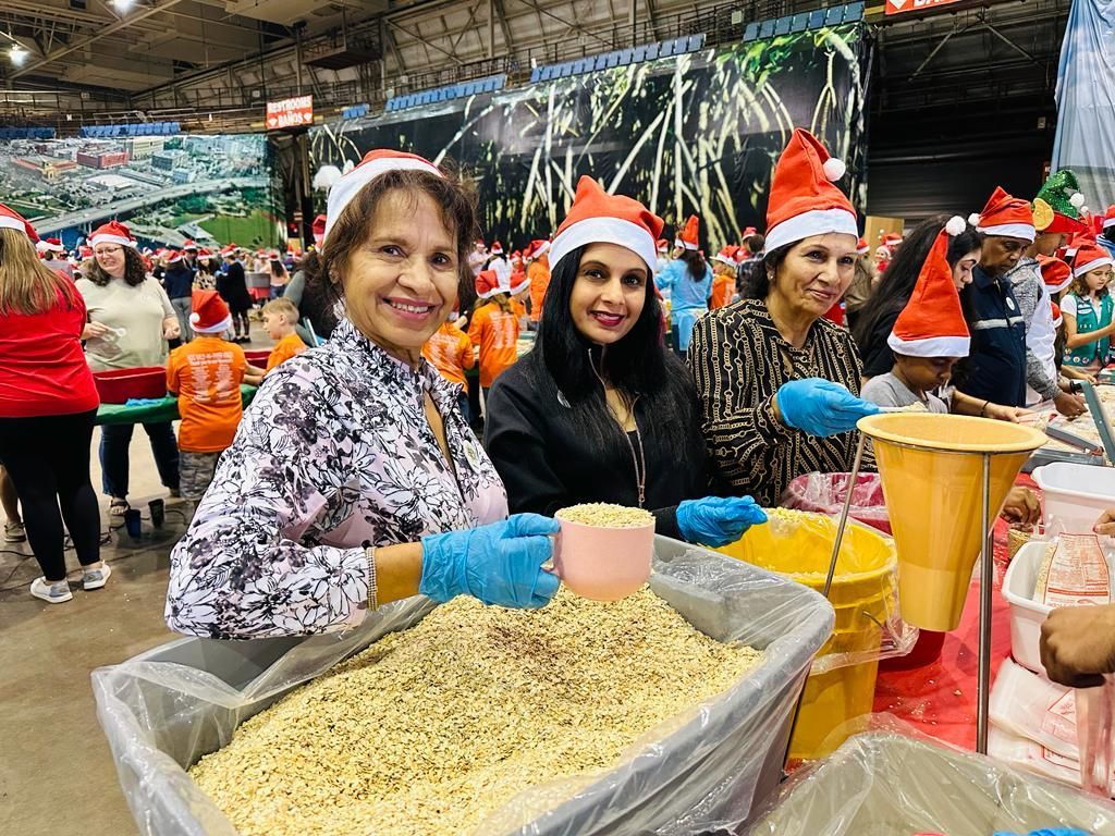 A group of women wearing santa hats are standing around a table.