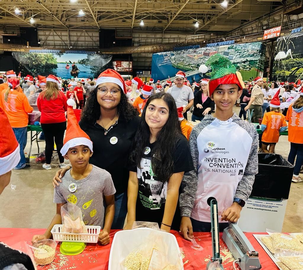 A group of people wearing santa hats are standing around a table.