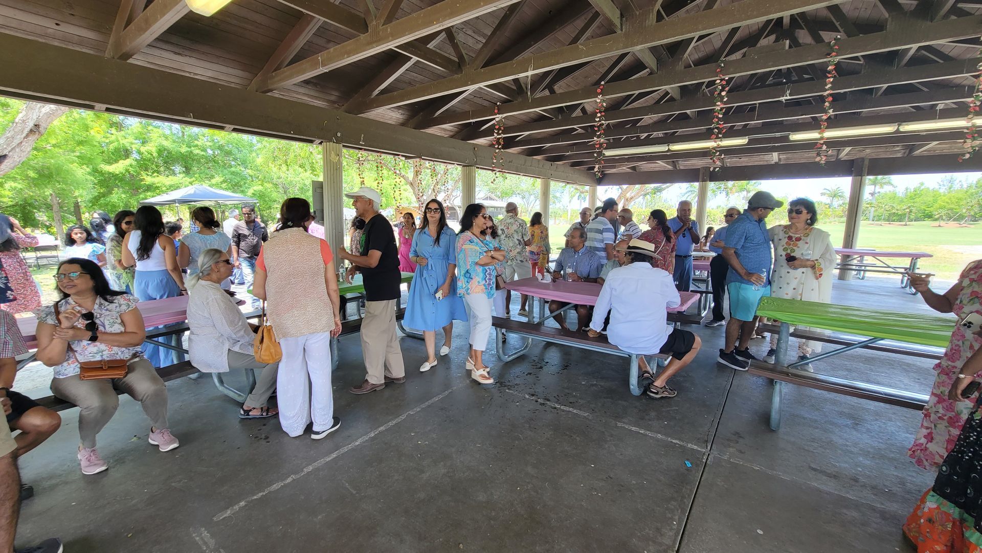 Group of people at a park under a pavilion; enjoying an outdoor gathering.