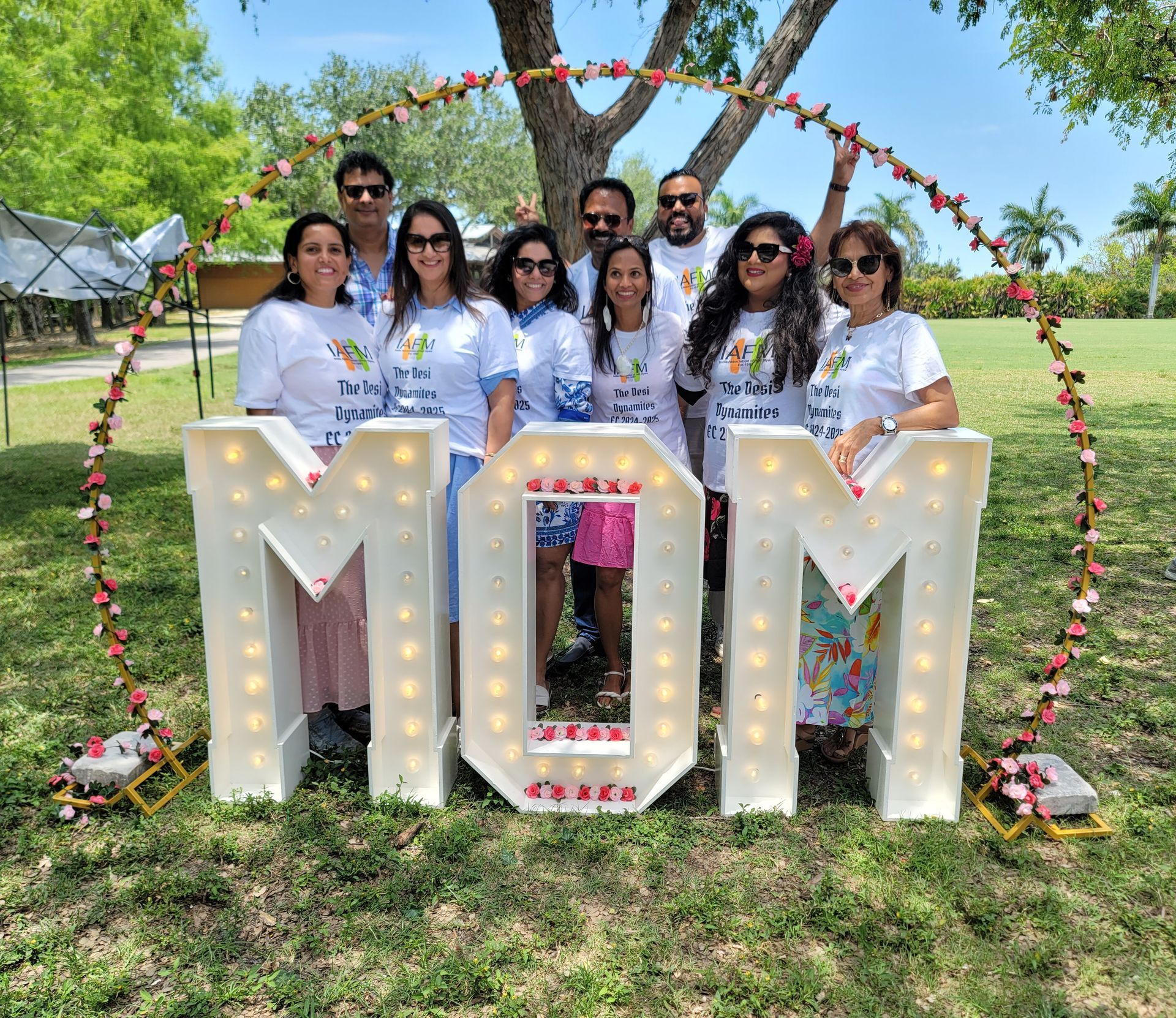 Group of people in white shirts, posing behind lit-up 