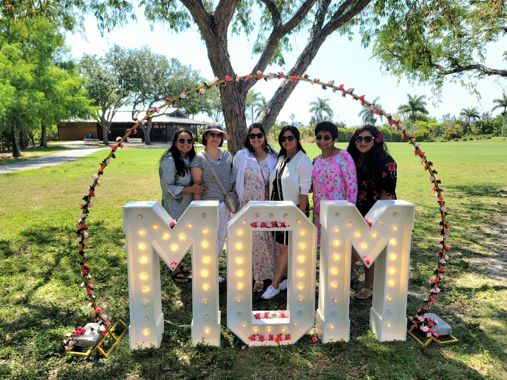 Six women pose in front of a lit 