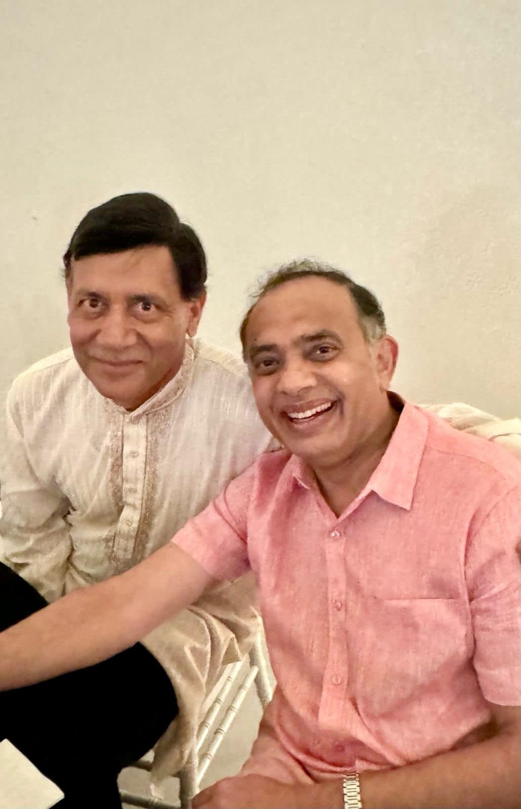 Two men are sitting next to each other and smiling for the camera.