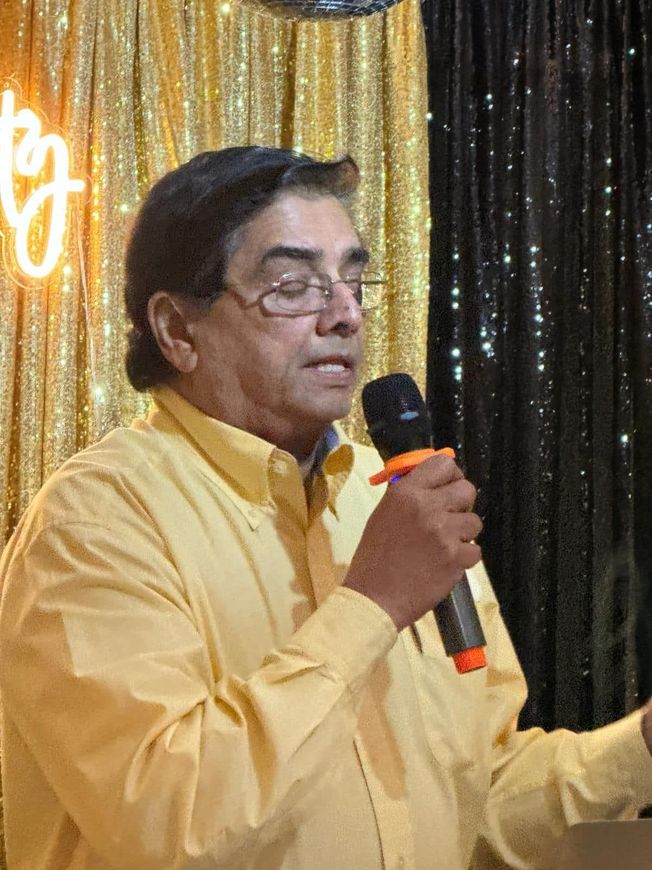 A man in a yellow shirt is holding a microphone