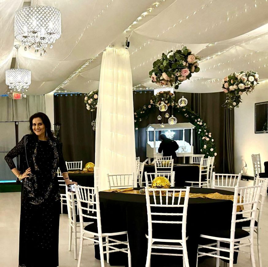 A woman in a black dress is standing in a room with tables and chairs
