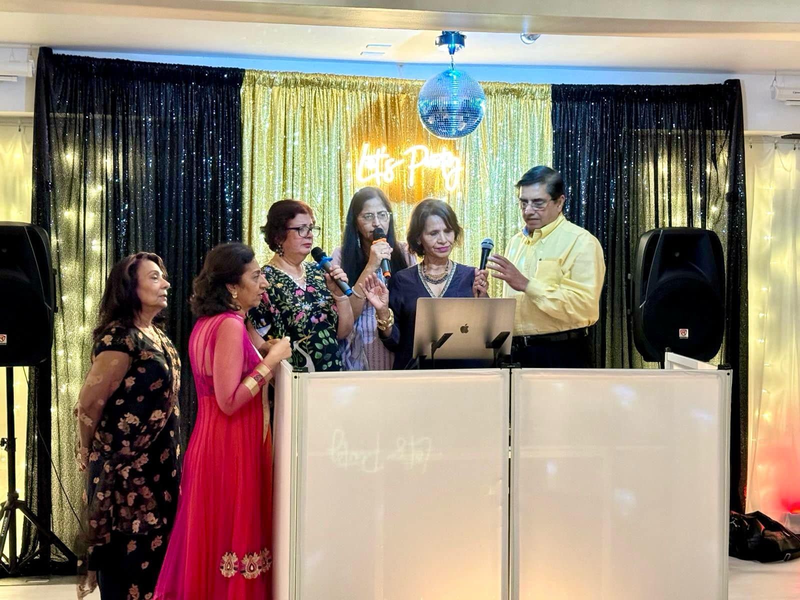 A group of people are standing around a dj booth at a party.