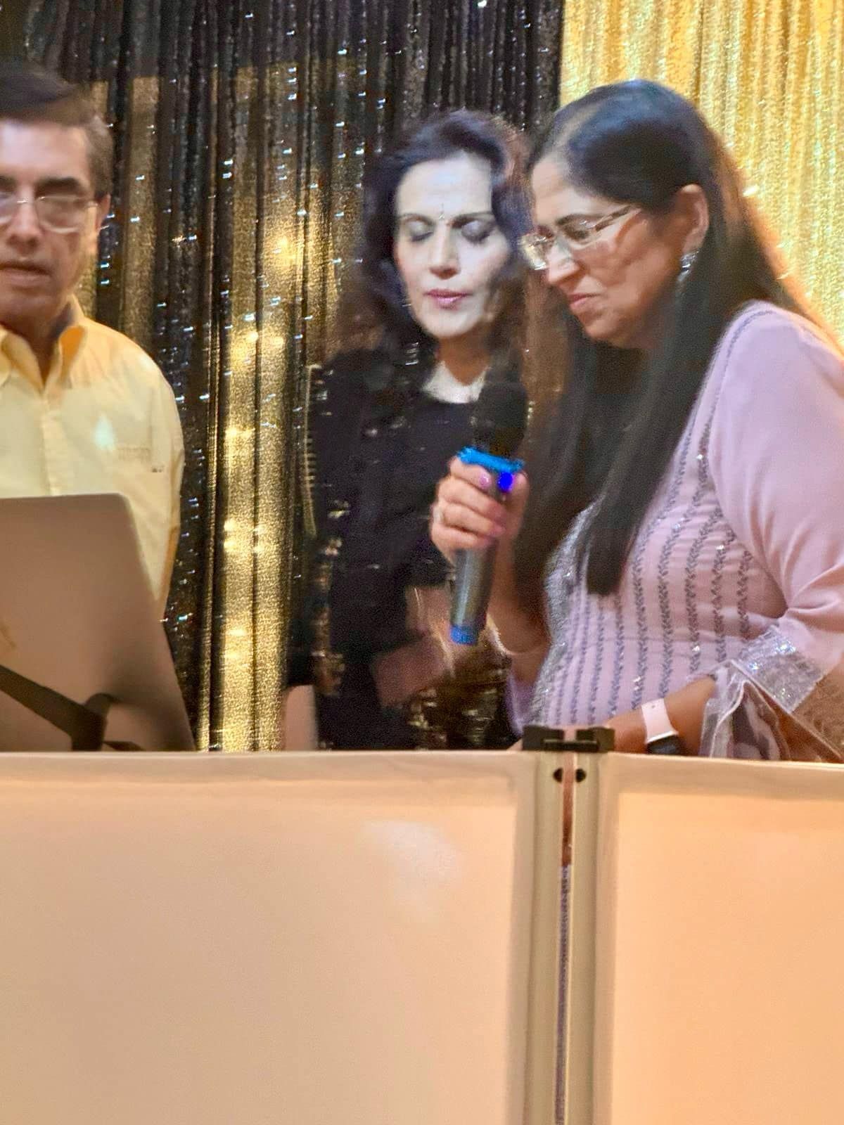 A woman is holding a microphone while standing next to a man and a woman.