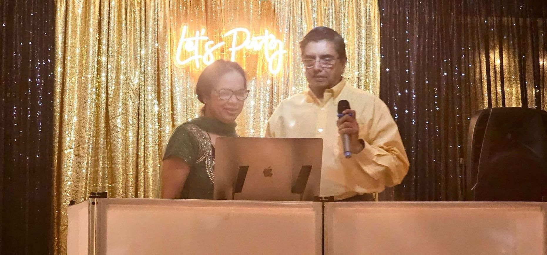 A man and a woman are standing in front of a laptop computer.