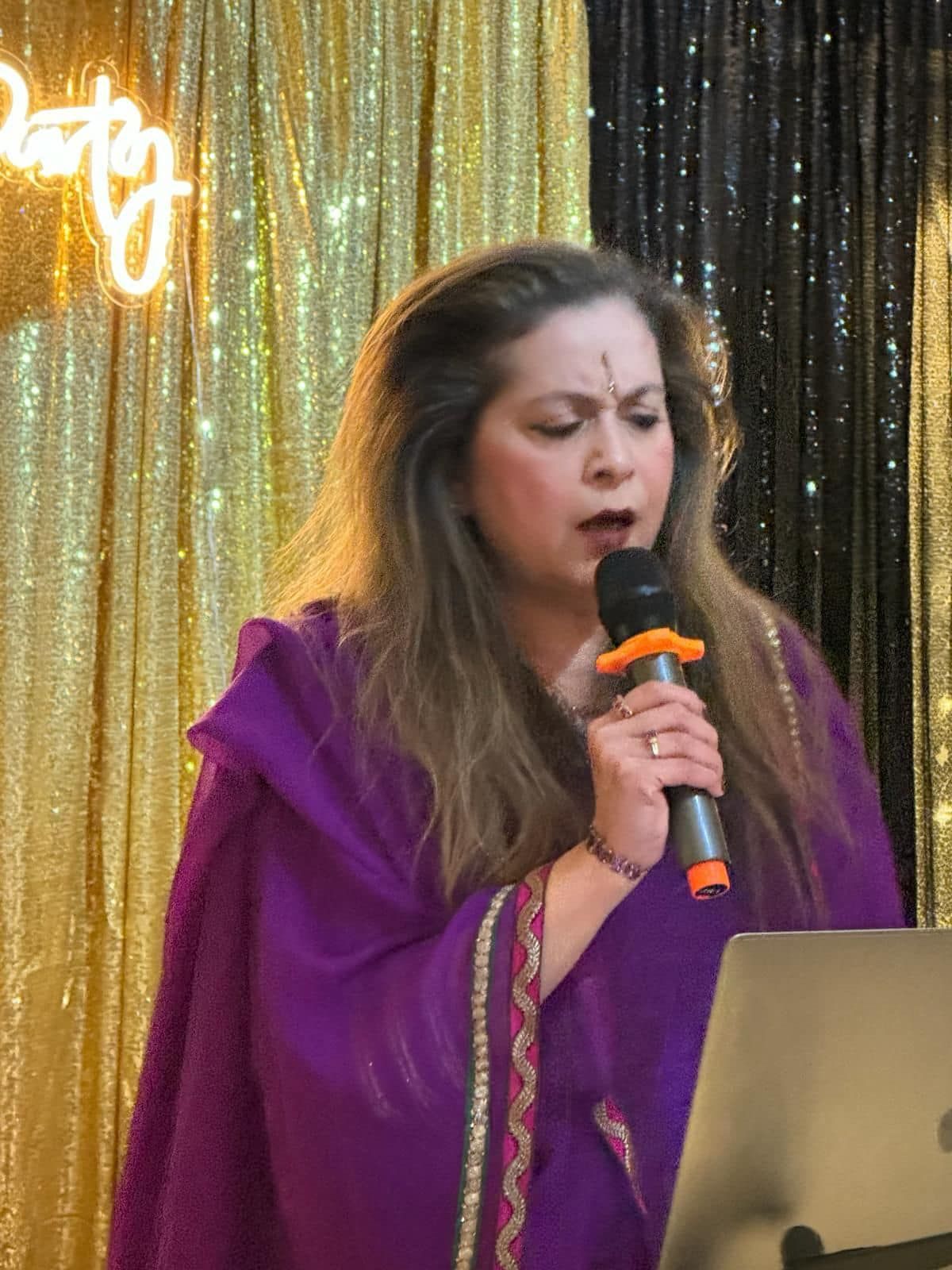 A woman in a purple dress is singing into a microphone.