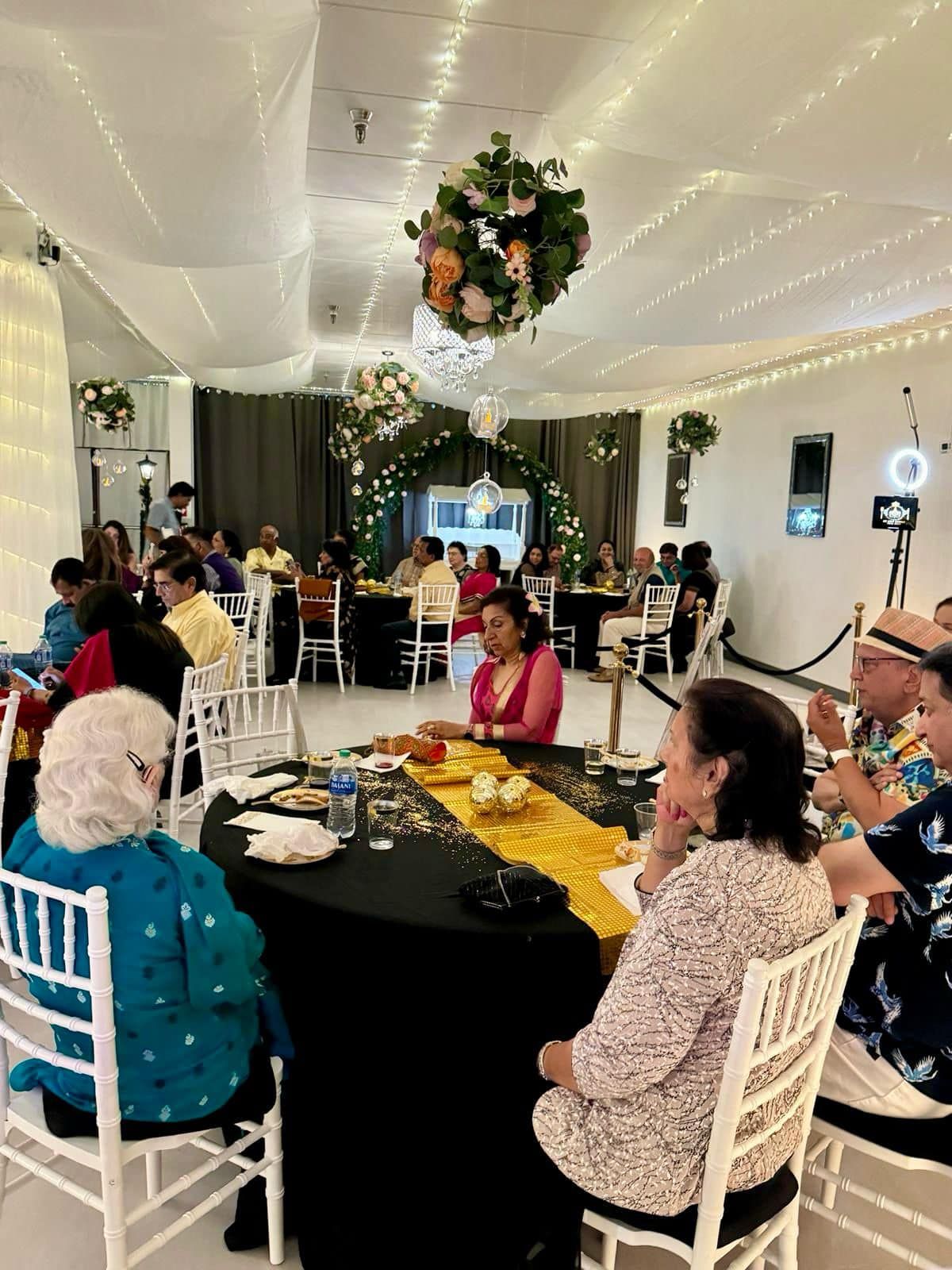 A group of people are sitting at tables in a room at a wedding reception.