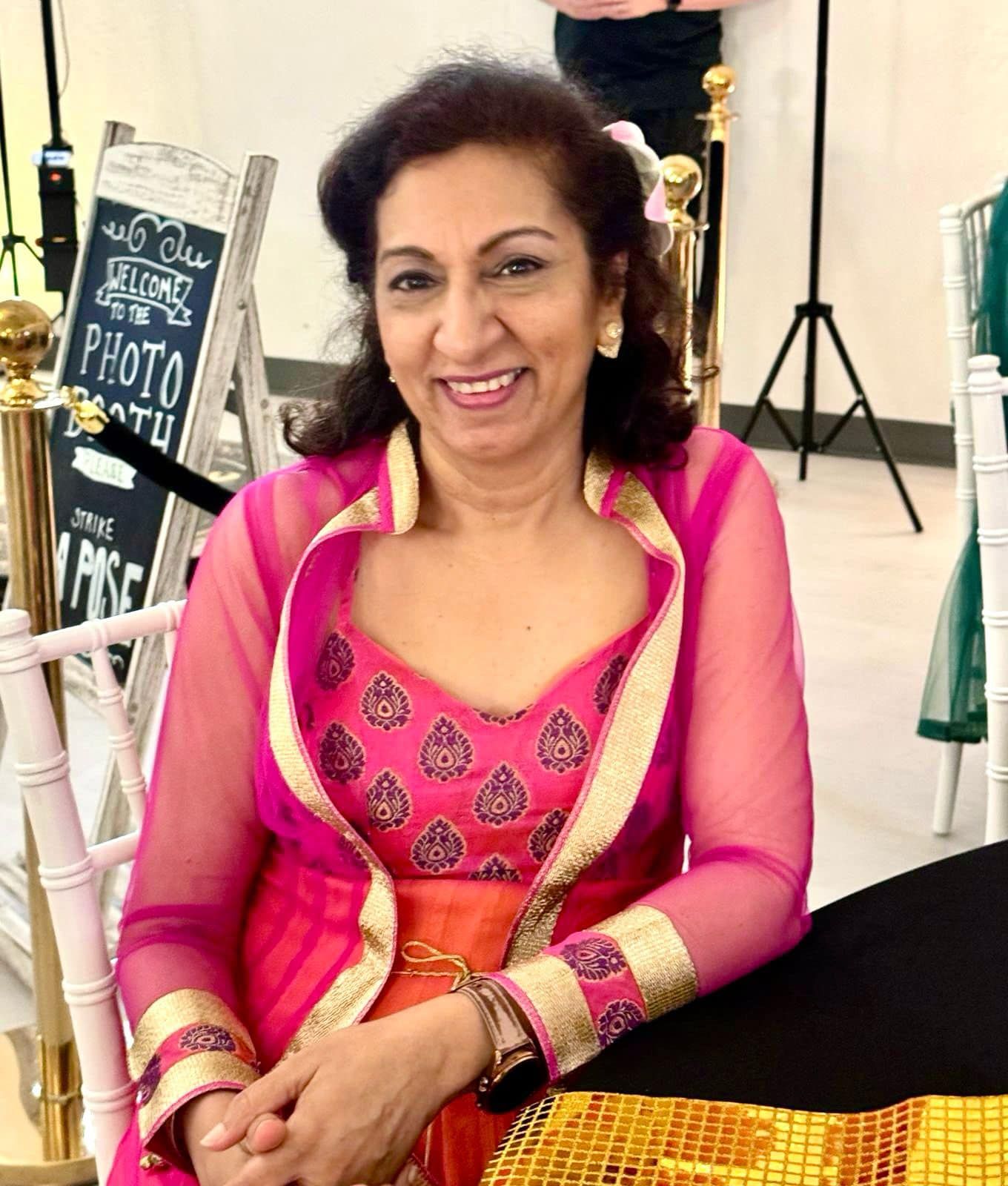 A woman in a pink and gold dress is sitting at a table.