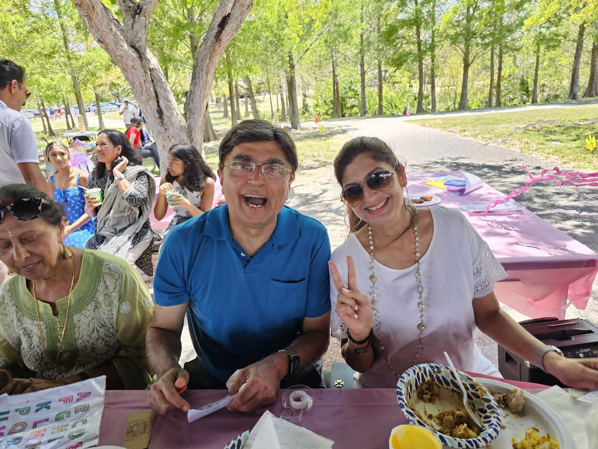 A group of people are sitting at a picnic table in a park.