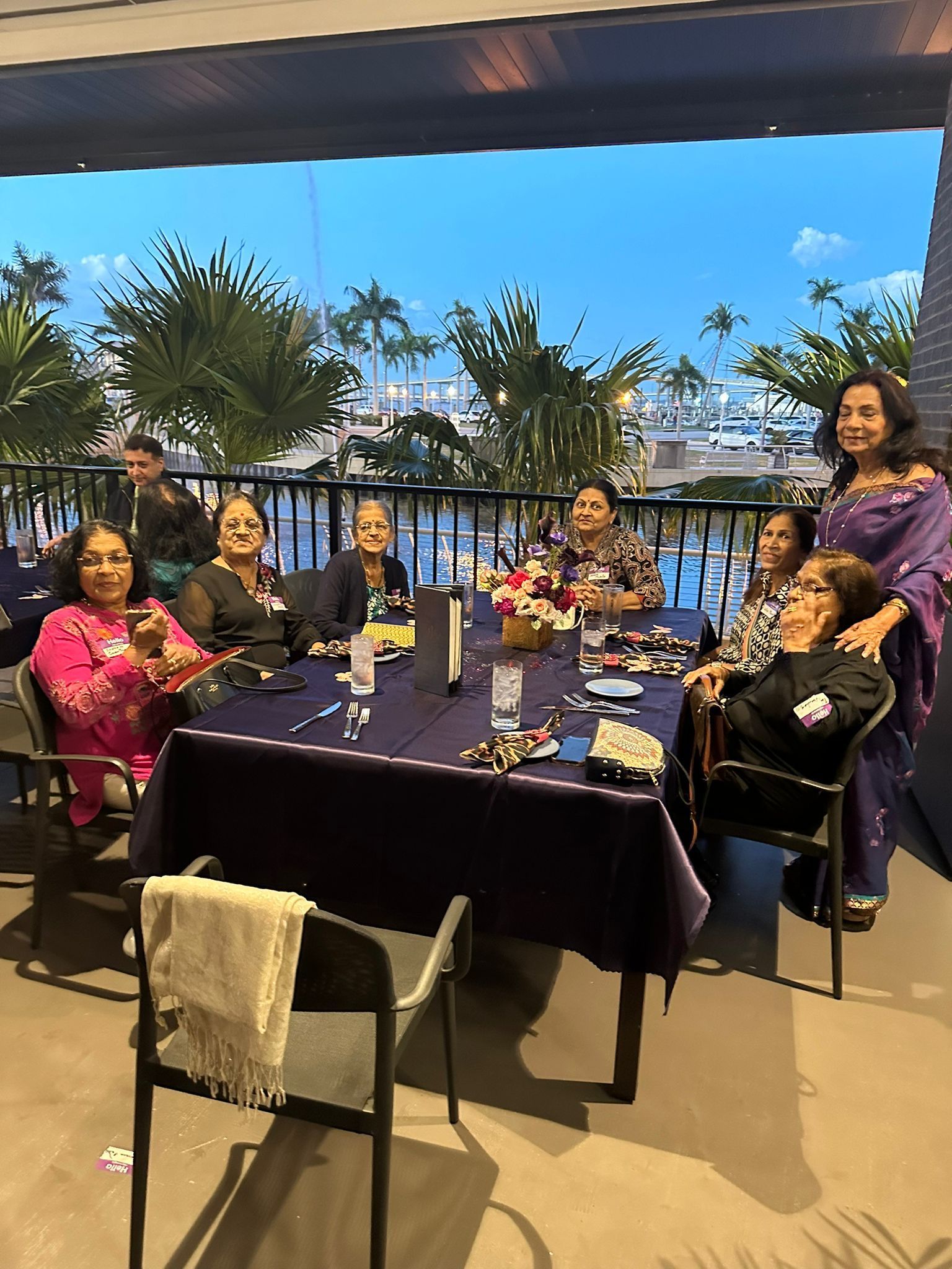 A group of women are sitting around a table on a balcony.