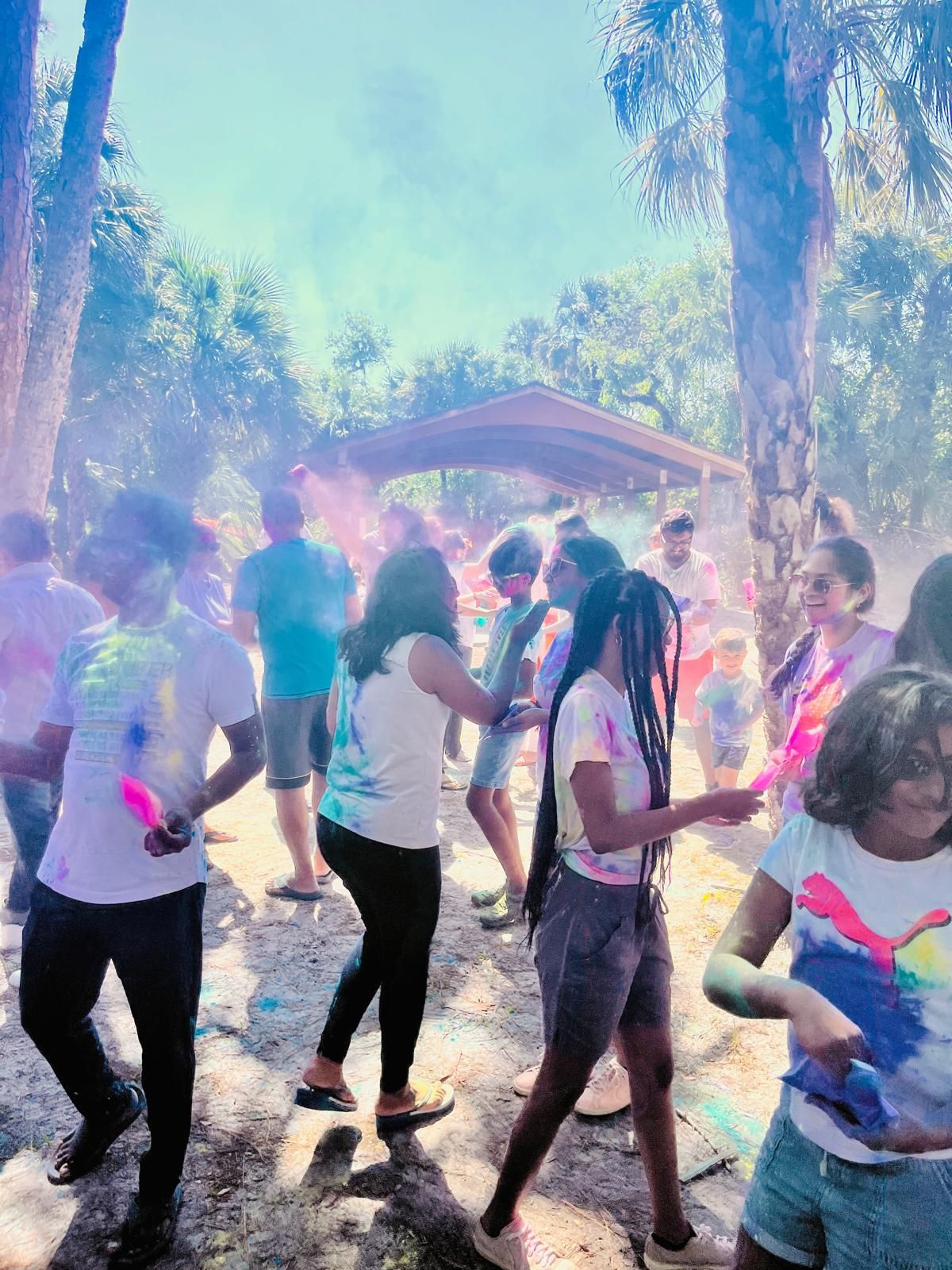 People throwing colorful powder at an outdoor festival.