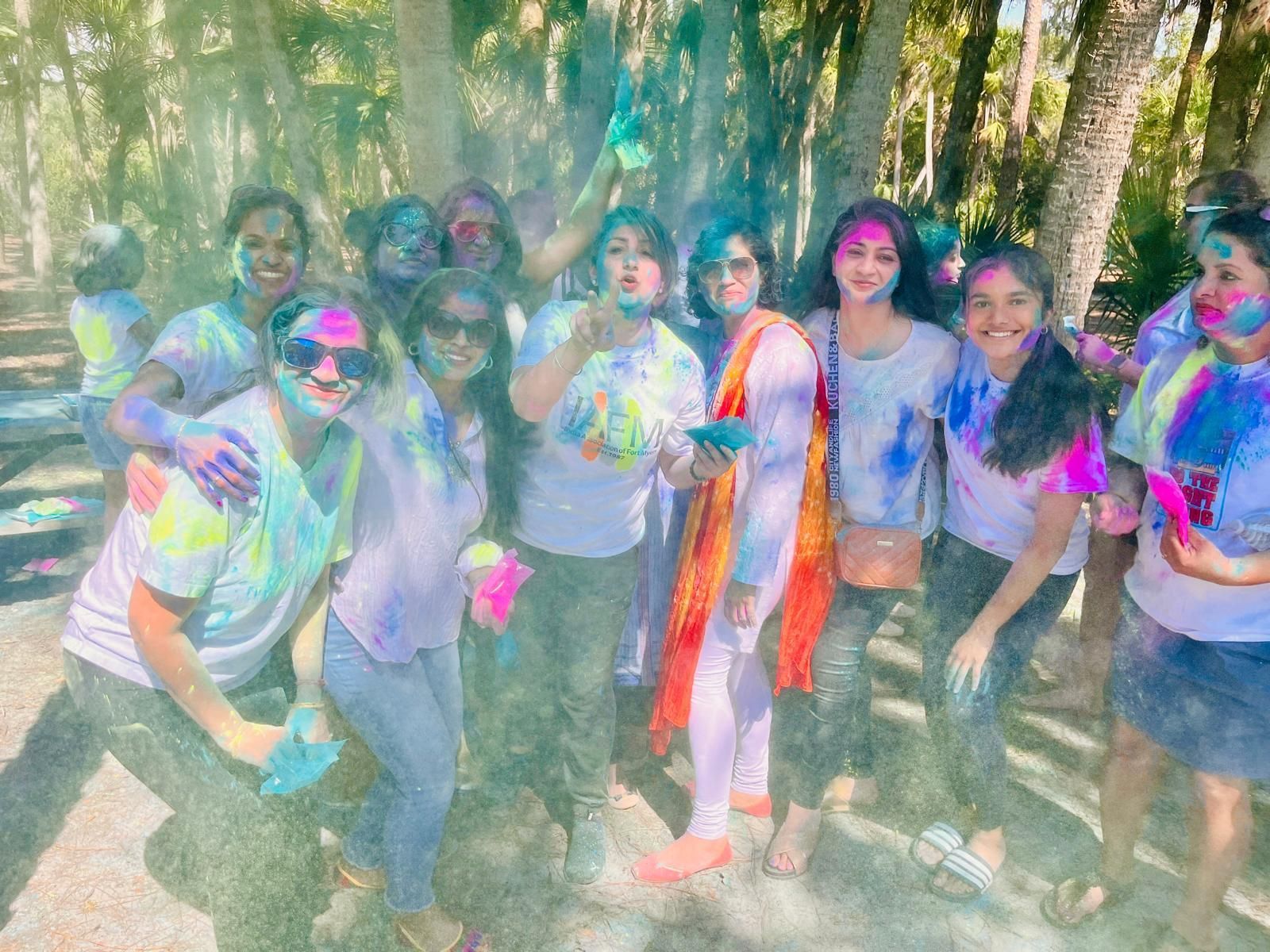 Group of people, covered in colorful powder, celebrating outdoors.