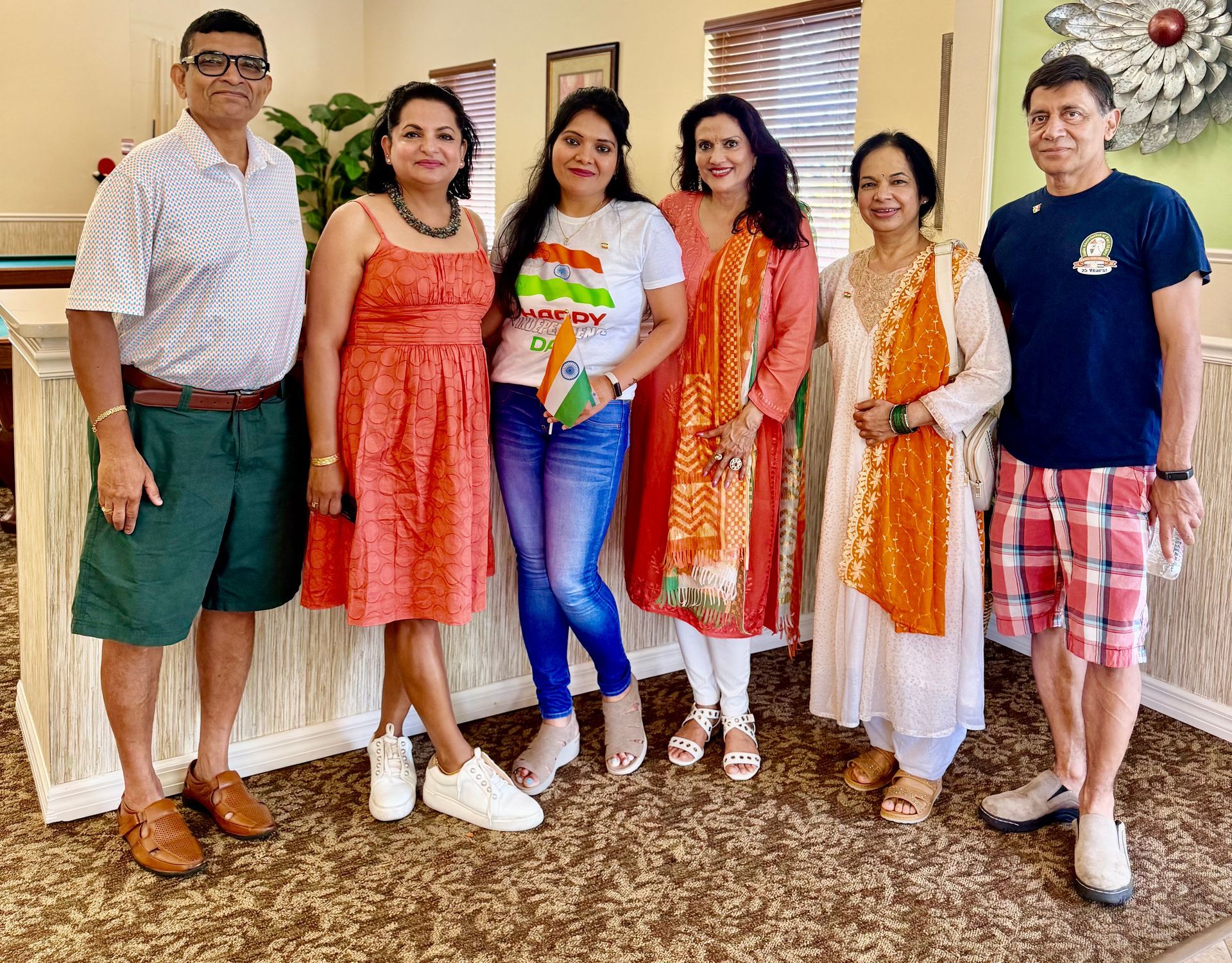 Group of six people posing indoors. Diverse clothing and expressions.