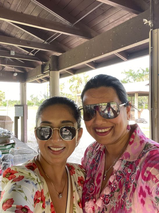 Two women wearing sunglasses are posing for a picture together.