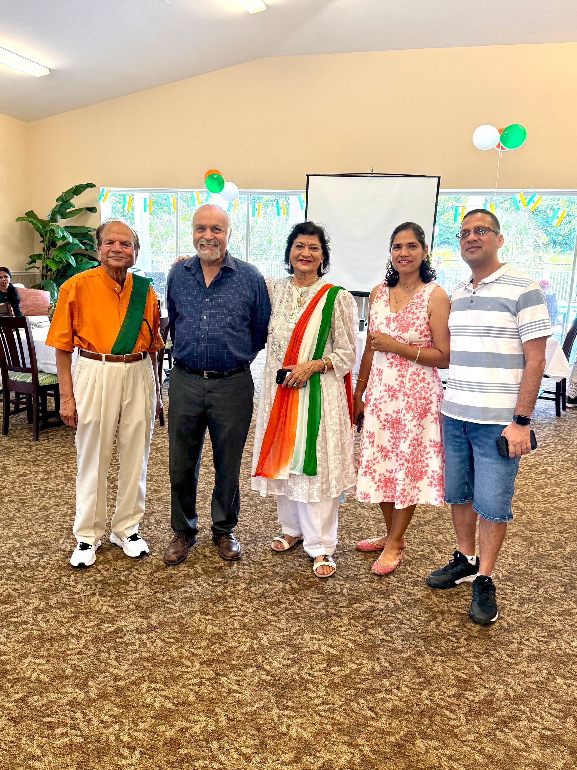 Five people smiling indoors, some wearing Indian flag colors.