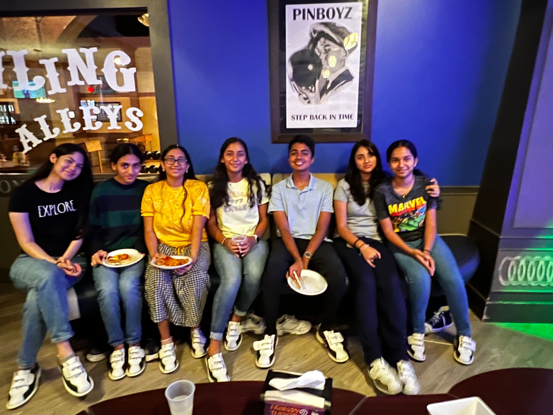 A group of young people are sitting on a couch eating pizza.
