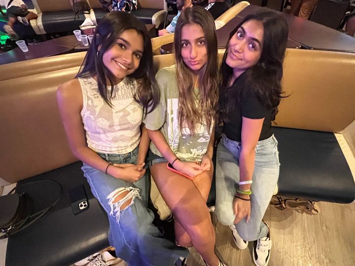 Three young women are posing for a picture while sitting on a couch.