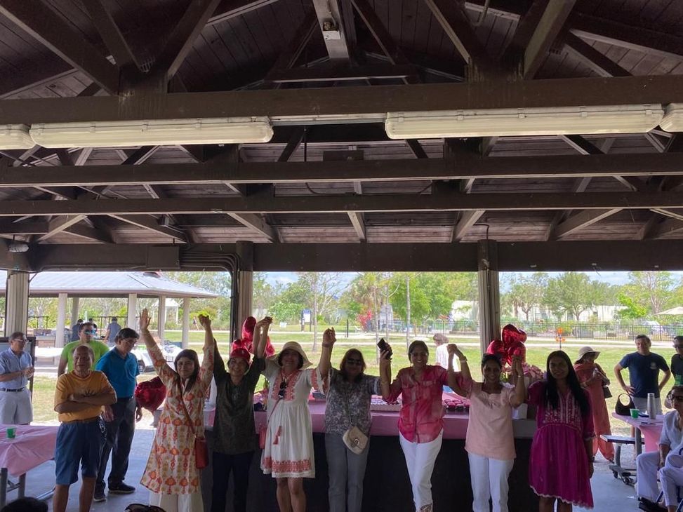 A group of people are standing under a pavilion with their hands in the air.