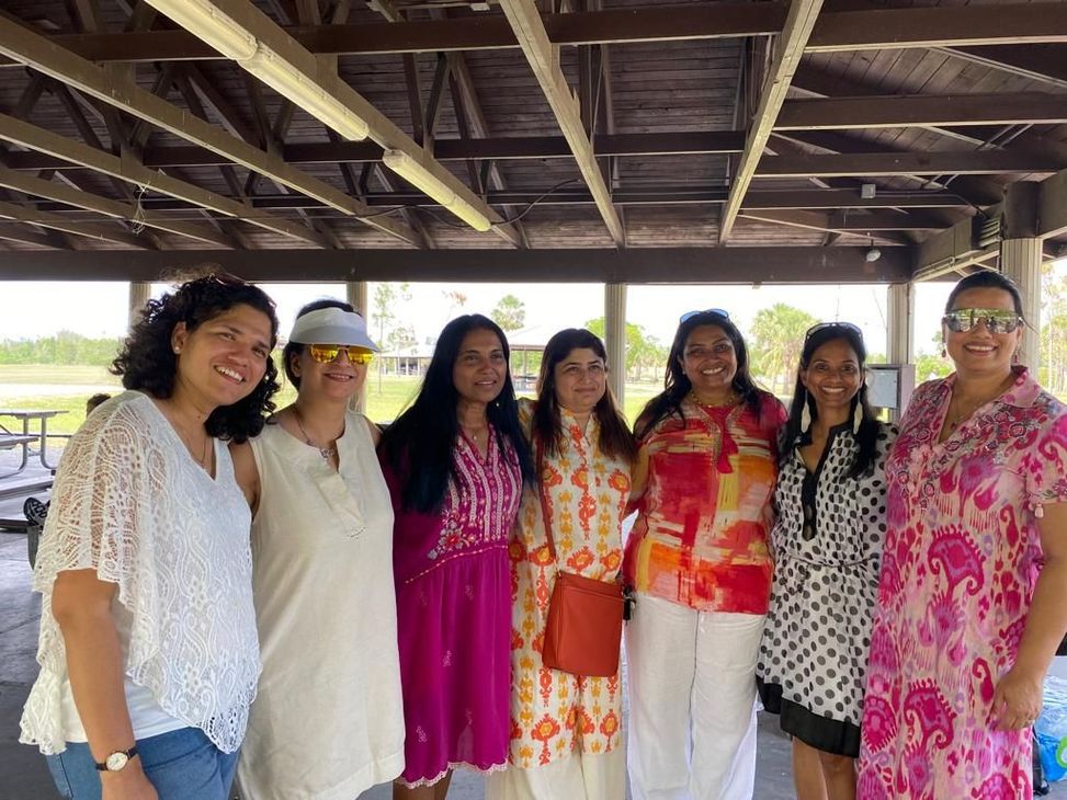 A group of women are posing for a picture under a pavilion.