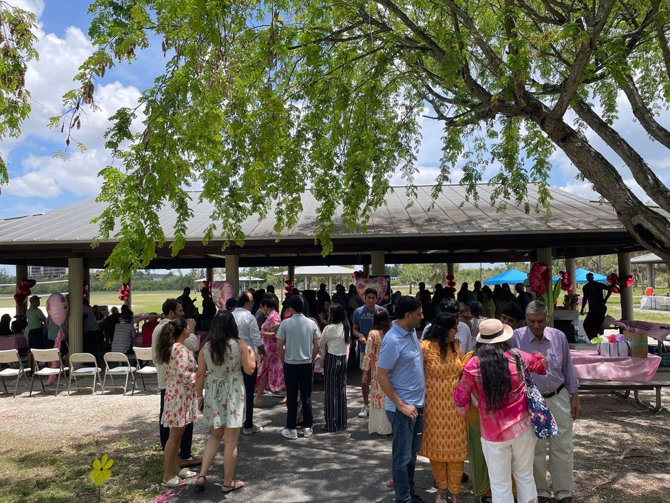 A group of people are standing under a pavilion in a park.