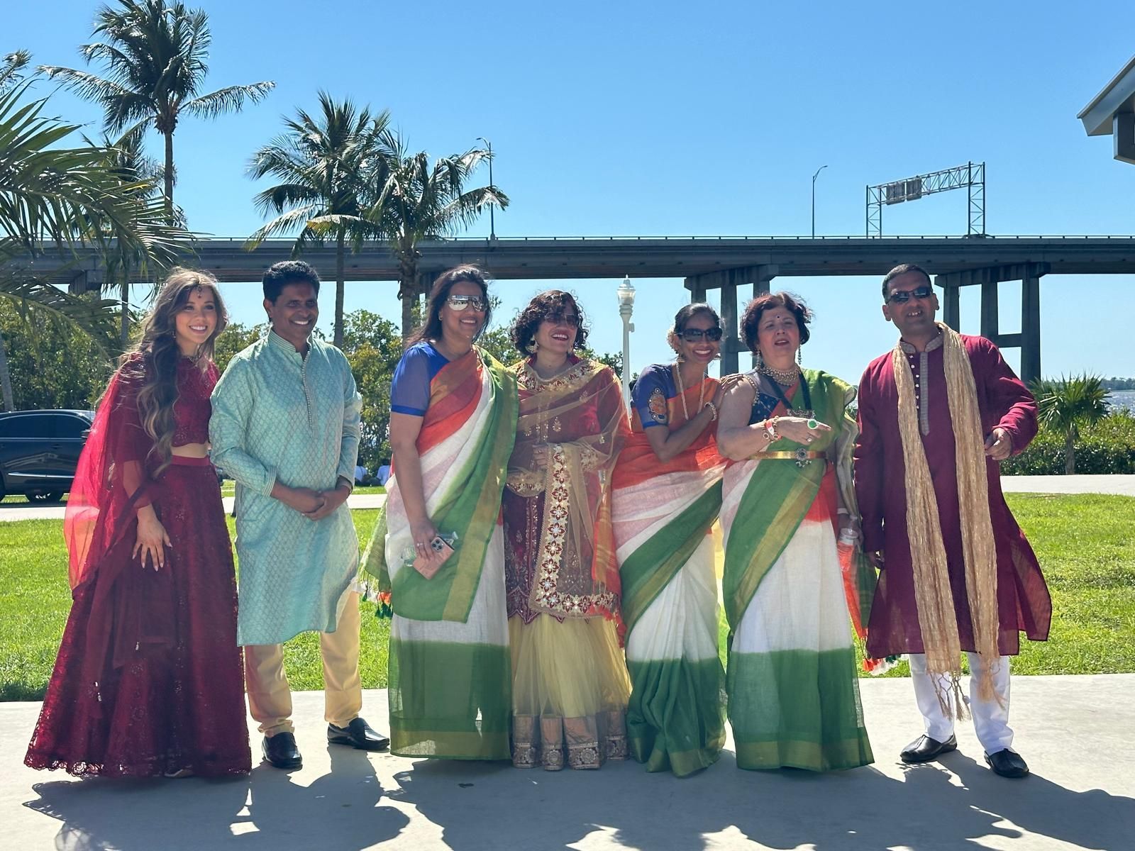 Group of people in colorful Indian attire pose outdoors.