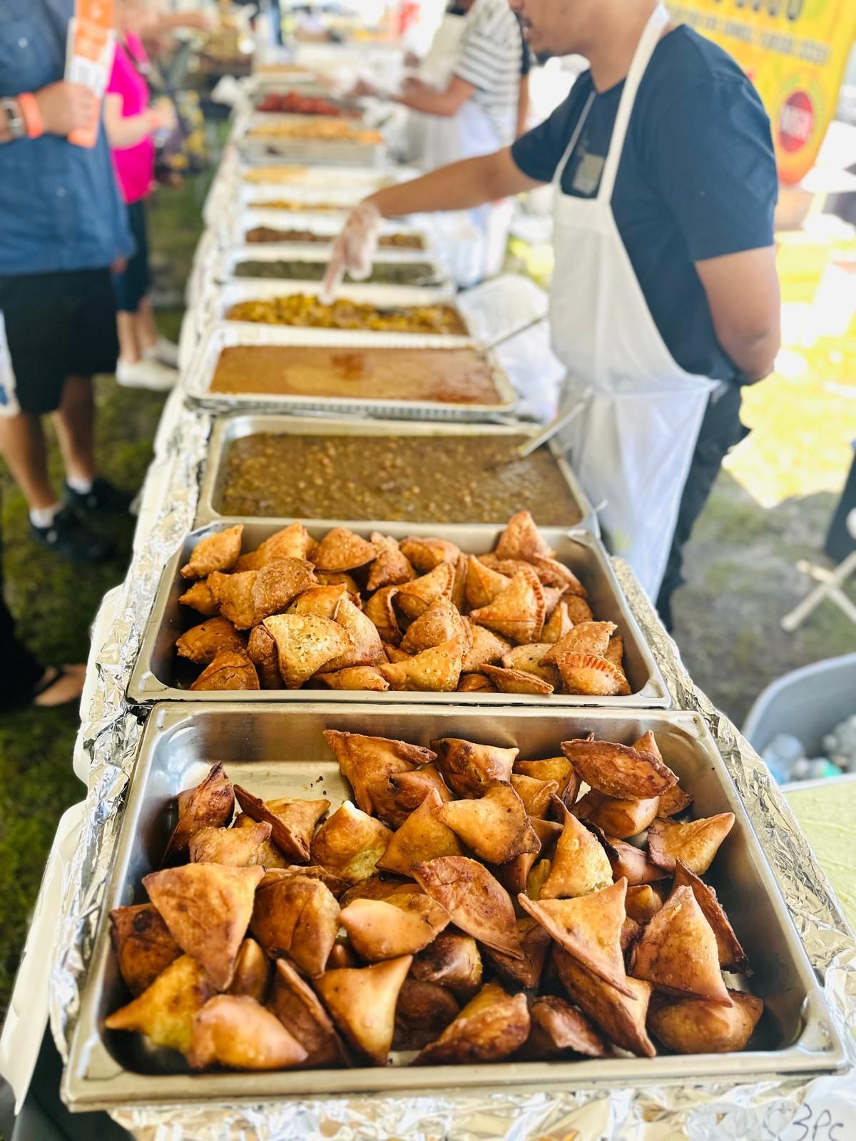 A food vendor serving samosas and other dishes at an outdoor event.