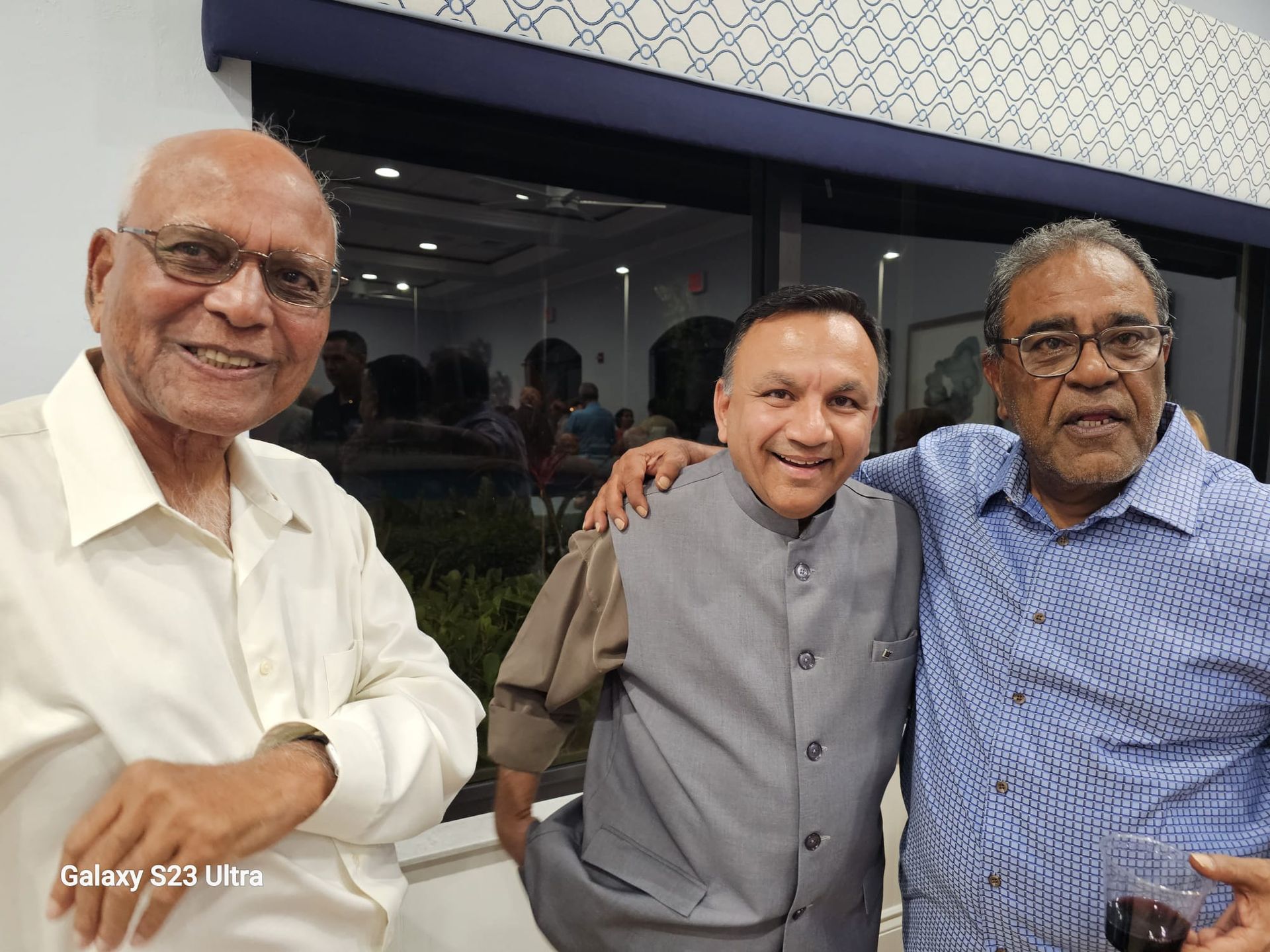 Three men are posing for a picture together in a room.
