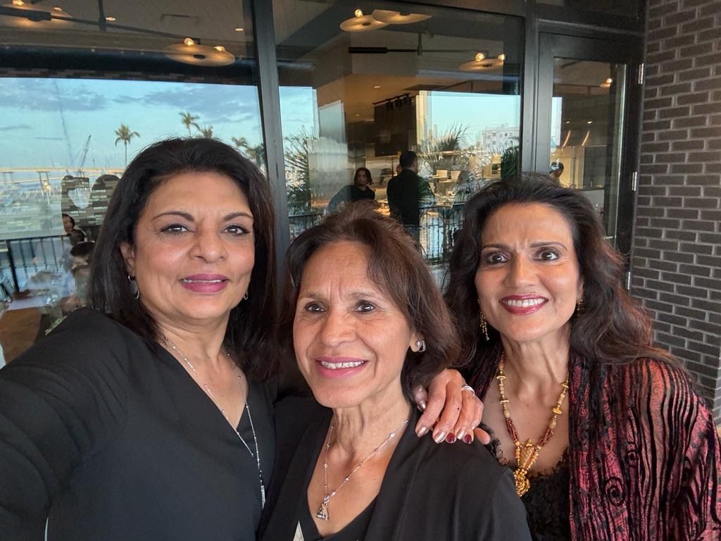 Three women are posing for a picture together in a restaurant.