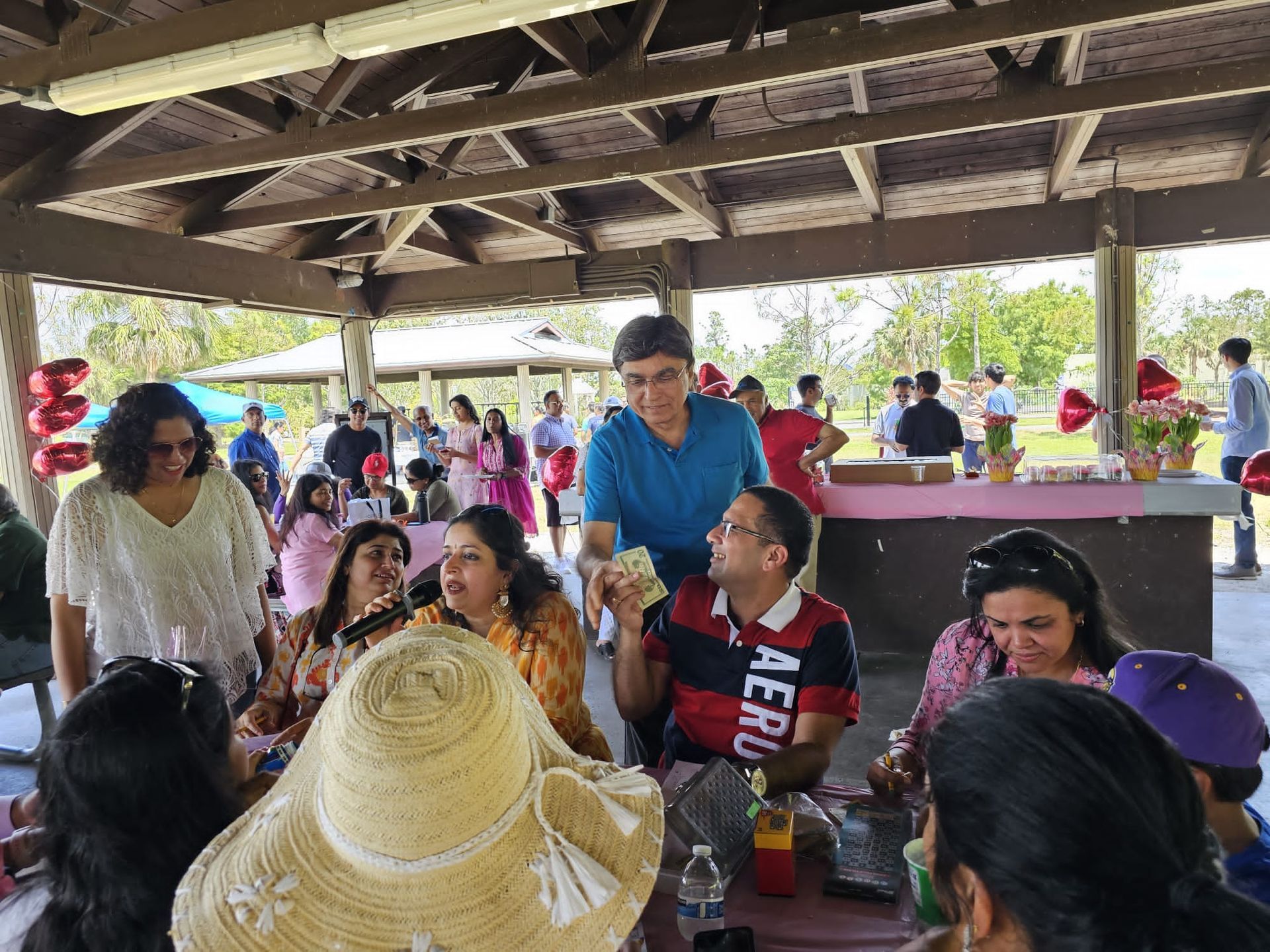 A group of people are sitting at tables under a pavilion.