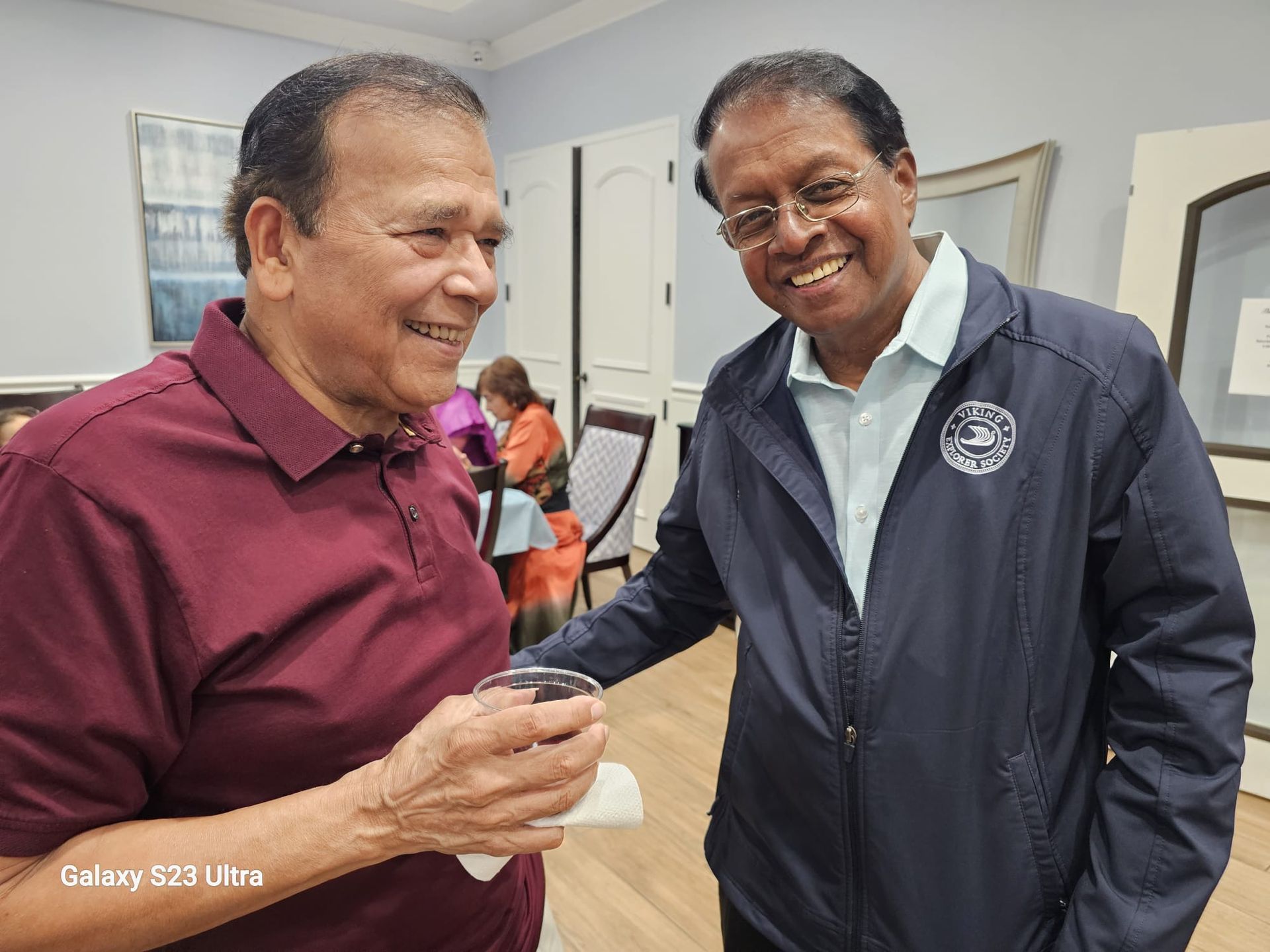 Two men are standing next to each other in a room and smiling.