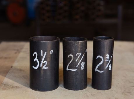 Three black cylindrical containers labeled 3½, 2⅞, and 2¾ on a wooden surface