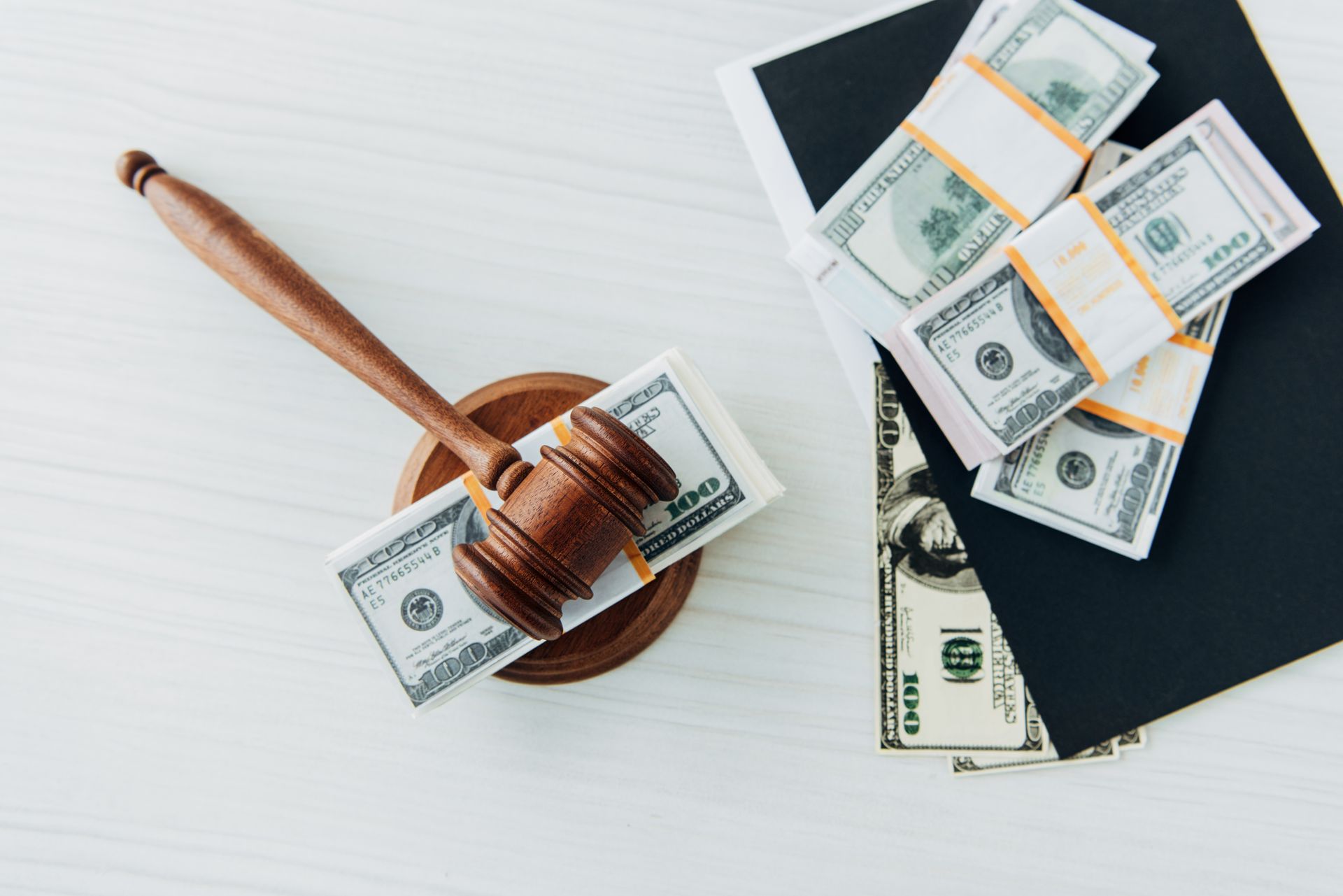 A wooden judge 's gavel is sitting on top of a pile of money.