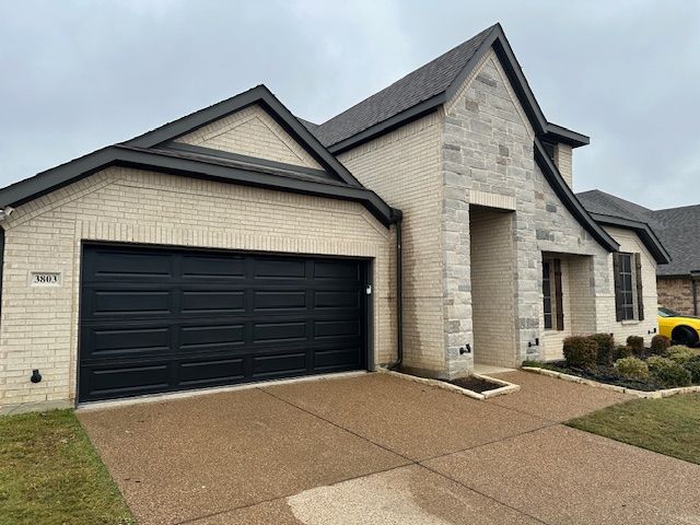 A house with a black garage door and a yellow car parked in front of it.