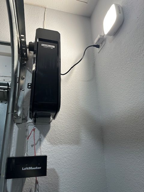 A garage door opener is hanging on a wall next to a light.